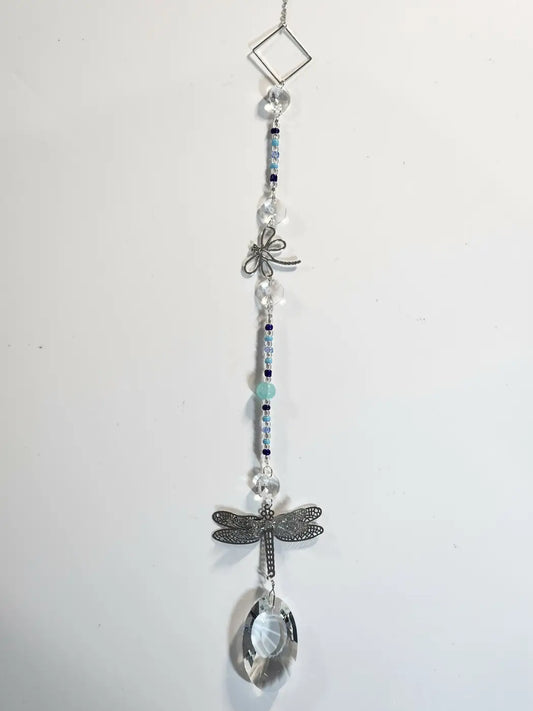 Long 6 silver dragonfly suncatcher with clear crystal beads hanging by suction cup in direct sunlight display