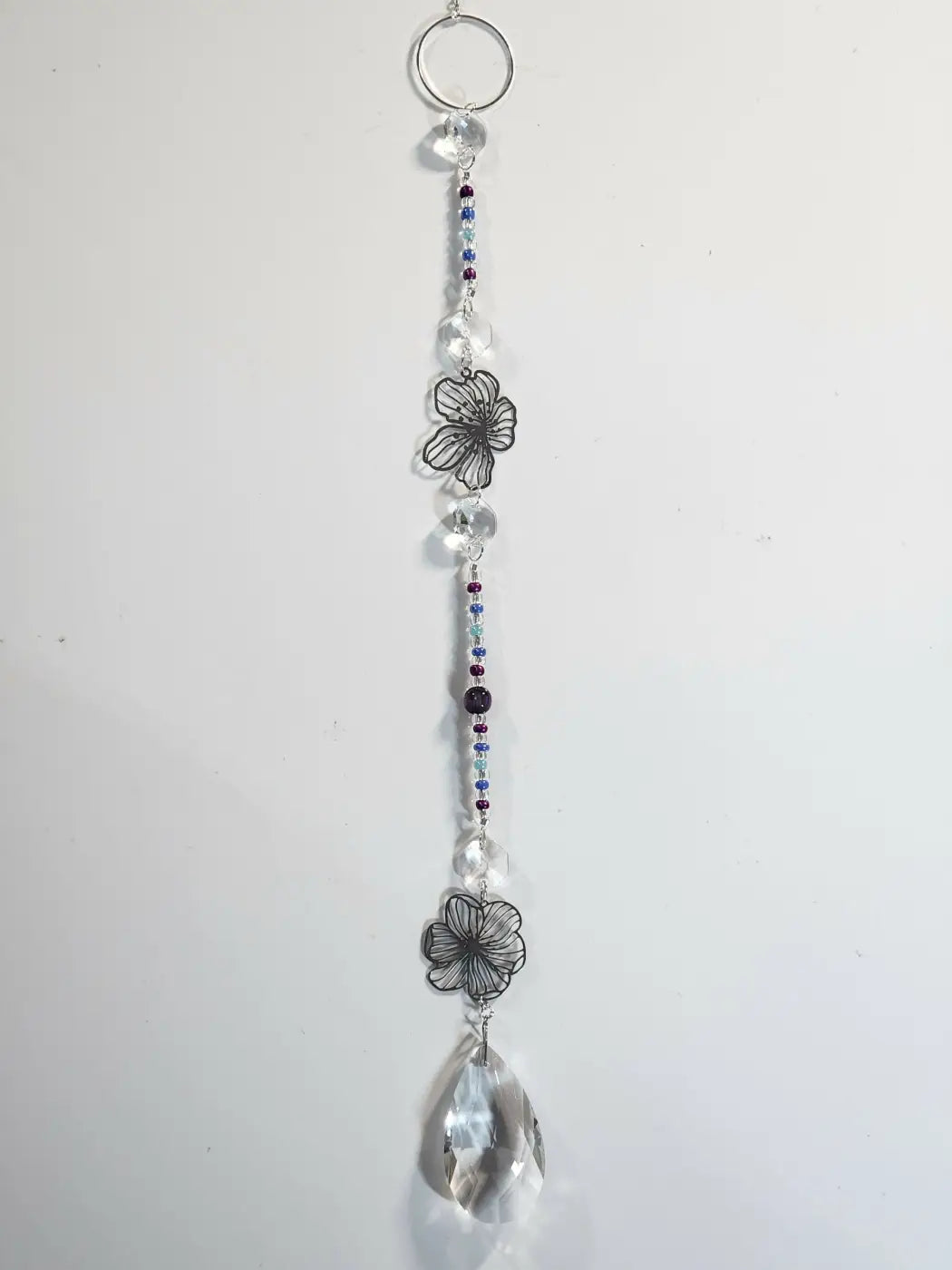 Long suncatcher with silver wire flower charms, clear and purple beads, and faceted teardrop crystal for direct sunlight decor