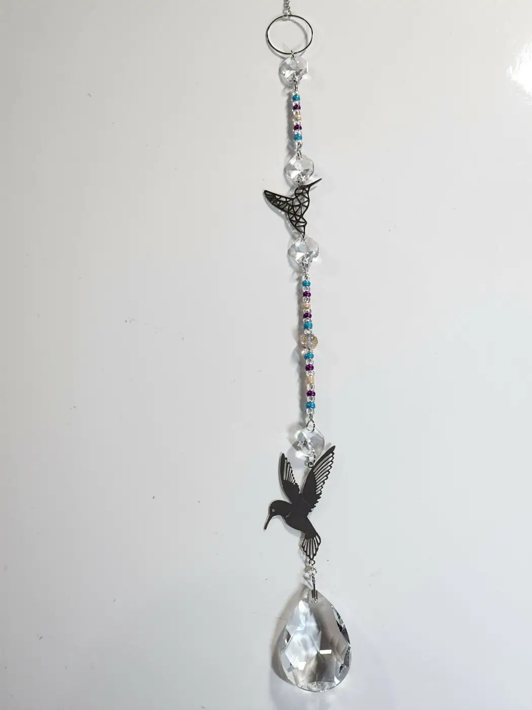 Long suncatcher featuring black metal hummingbird cutouts, clear crystal beads, and a teardrop prism for direct sunlight