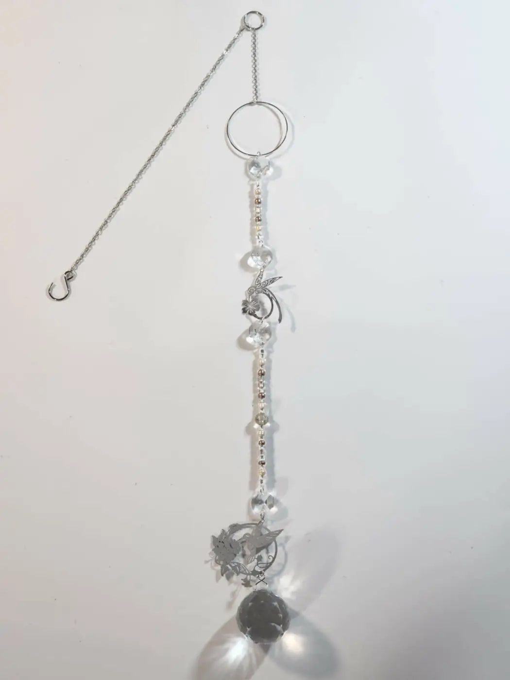 Silver-toned long suncatcher with clear crystal beads and floral metal charms designed for direct sunlight display