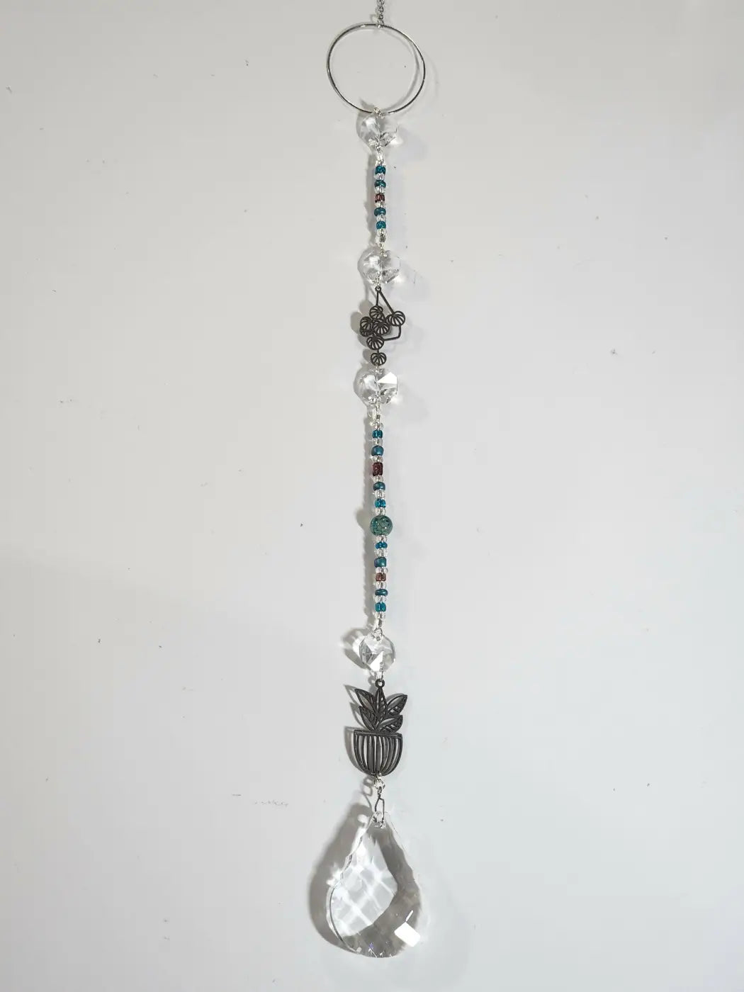 Long suncatcher with clear crystal, teal and brown beads, silver metal ring, and teardrop prism for direct sunlight