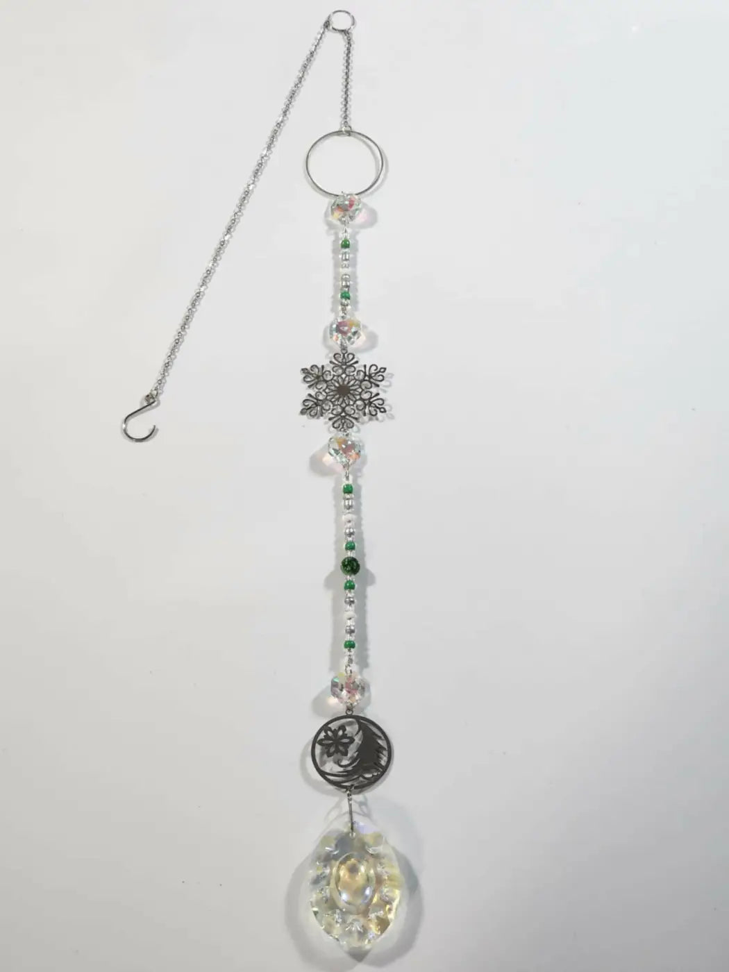 Long suncatcher with silver toned snowflake and crescent moon charms, clear and green beads for direct sunlight decor