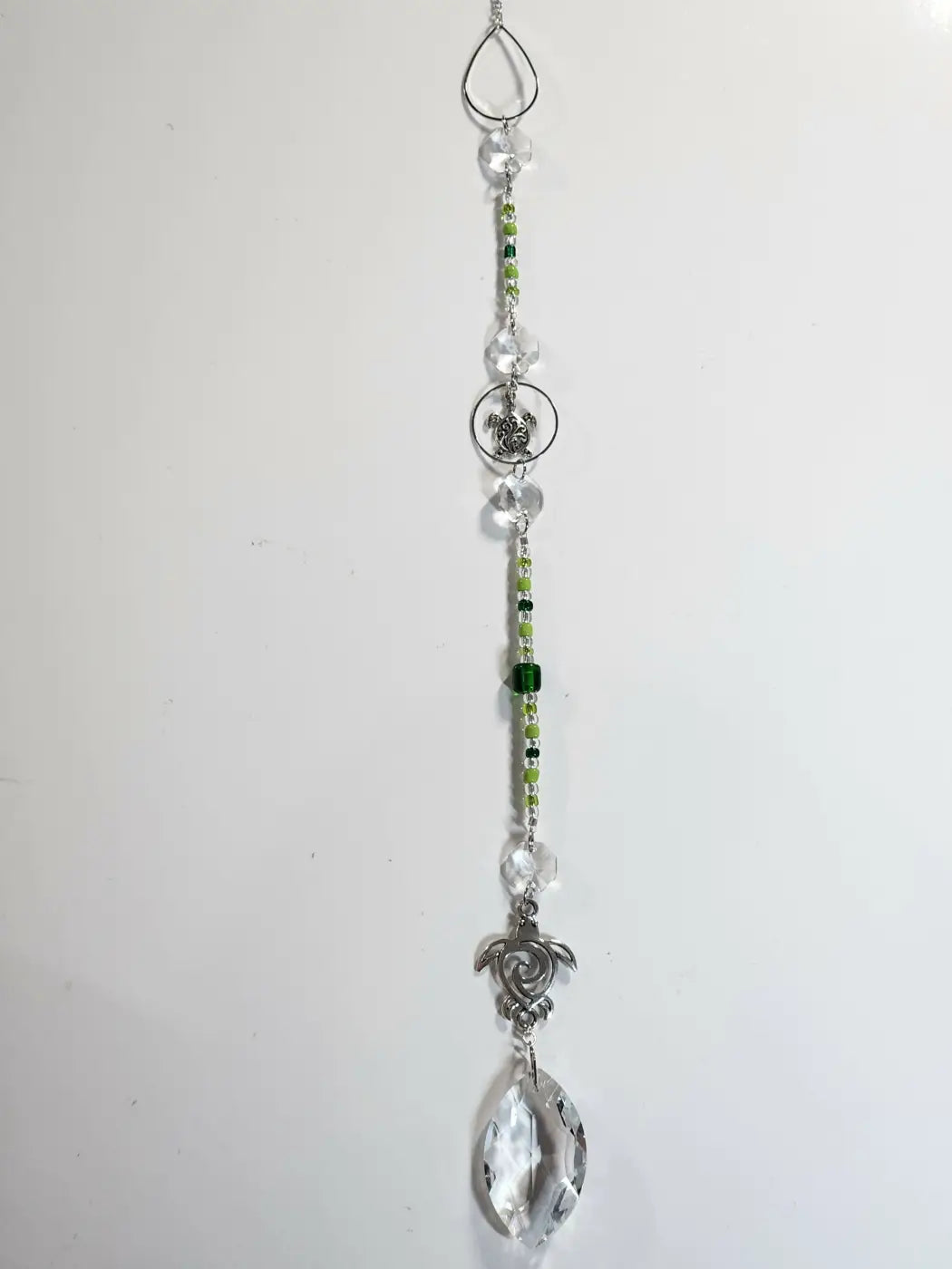 Long suncatcher with clear crystal and green seed beads on silver chain featuring ornate turtle charms for direct sunlight