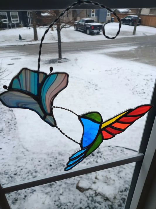 Colorful stained glass midflight hummingbird feeding ornament with vibrant blue green red yellow and teal hues