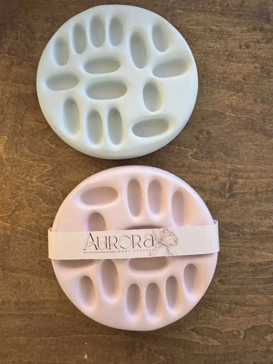 Multi ring holder featuring white and pale pink circular bath sponges with textured oval-patterned surface