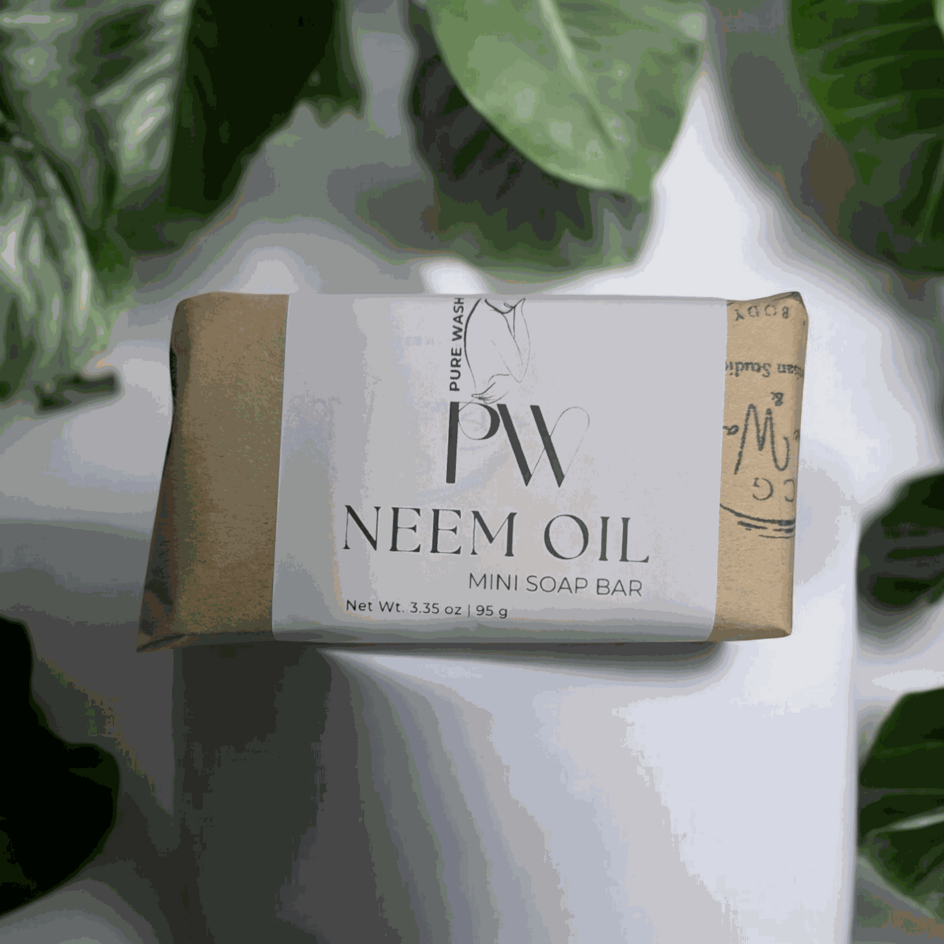 Mini soap bar with neem oil, eco-friendly packaging, surrounded by green leaves.