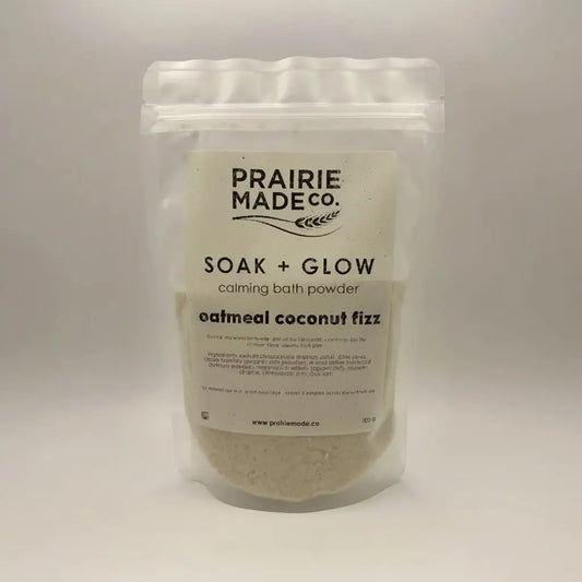 A clear resealable pouch of Prairie Made Co soak + glow calming bath oatmeal coconut fizz sprinkle with white label
