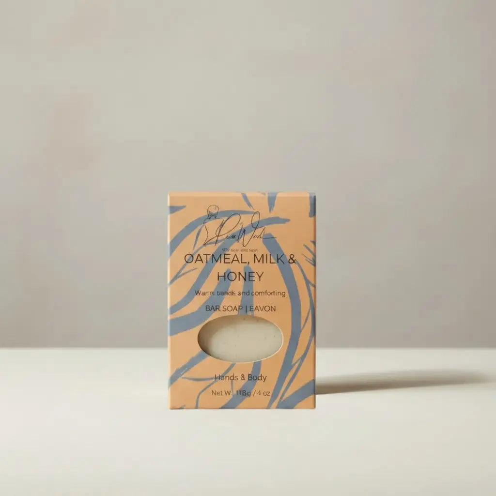 A creamy white oatmeal milk and honey soap bar in a peach box with blue leafy patterns best for dry skin