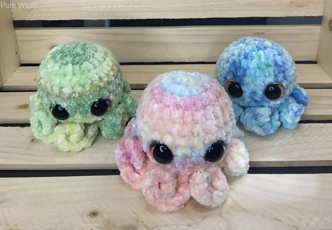 Three handmade crocheted octopus plushies in pastel green blue and pink with black bead eyes for natural skincare canada decor