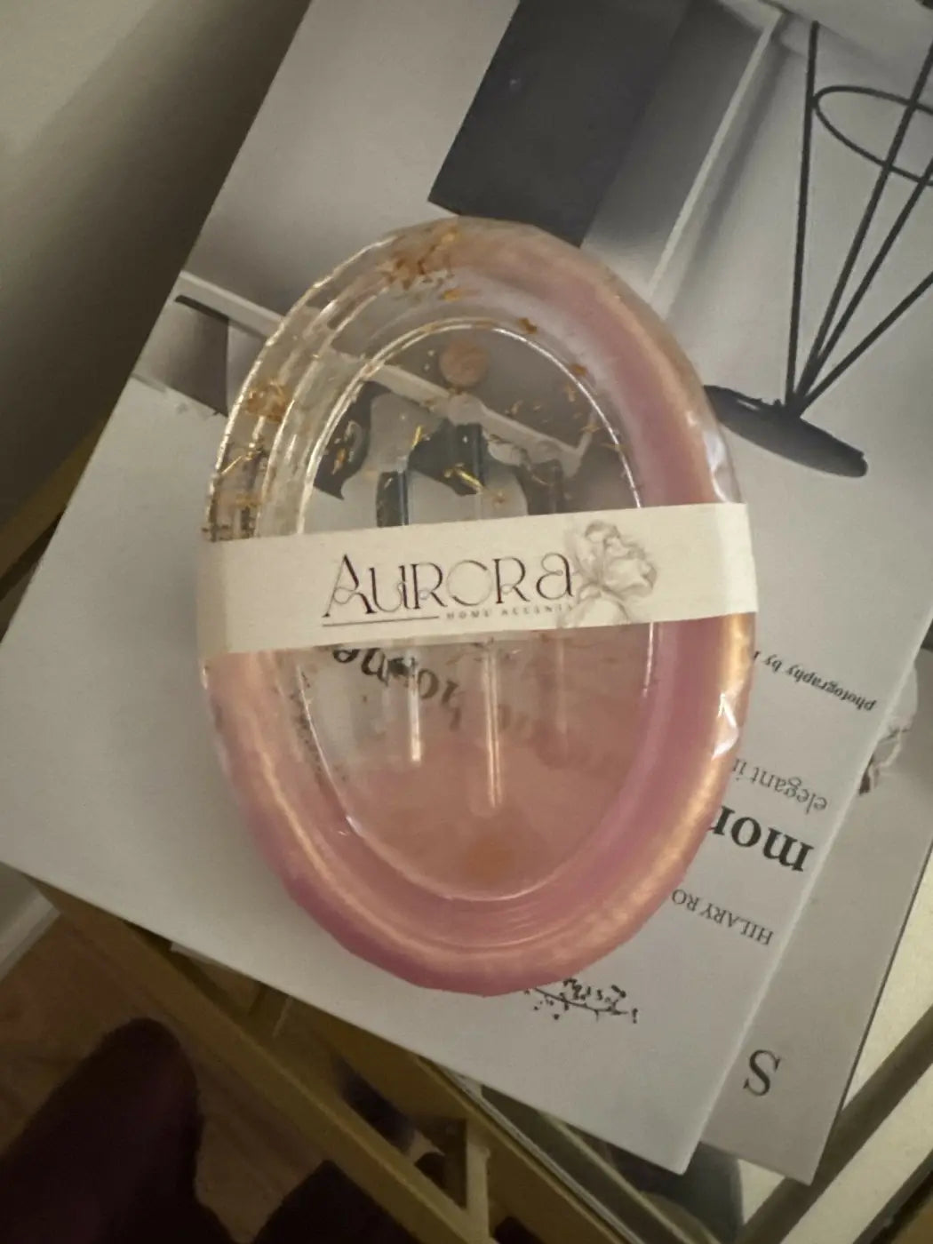 Oval soap dish holding a pink translucent soap bar with gold flecks wrapped in clear plastic labeled aurora