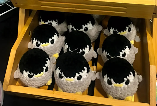 Adorable handmade crocheted black-and-white penguin plush toys with yellow beaks in wooden display box for natural skincare canada