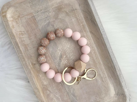 Pink floral wristlet featuring baby pink beads and speckled beige silicone beaded wristlets with a gold clasp