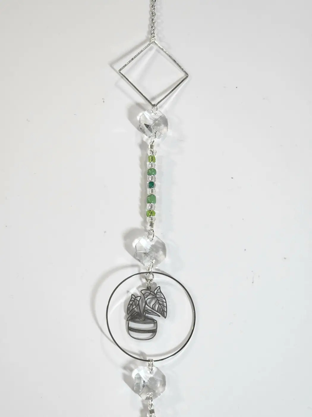 Delicate silver plant long suncatcher with geometric diamond frame clear crystals green gemstones and central potted plant charm