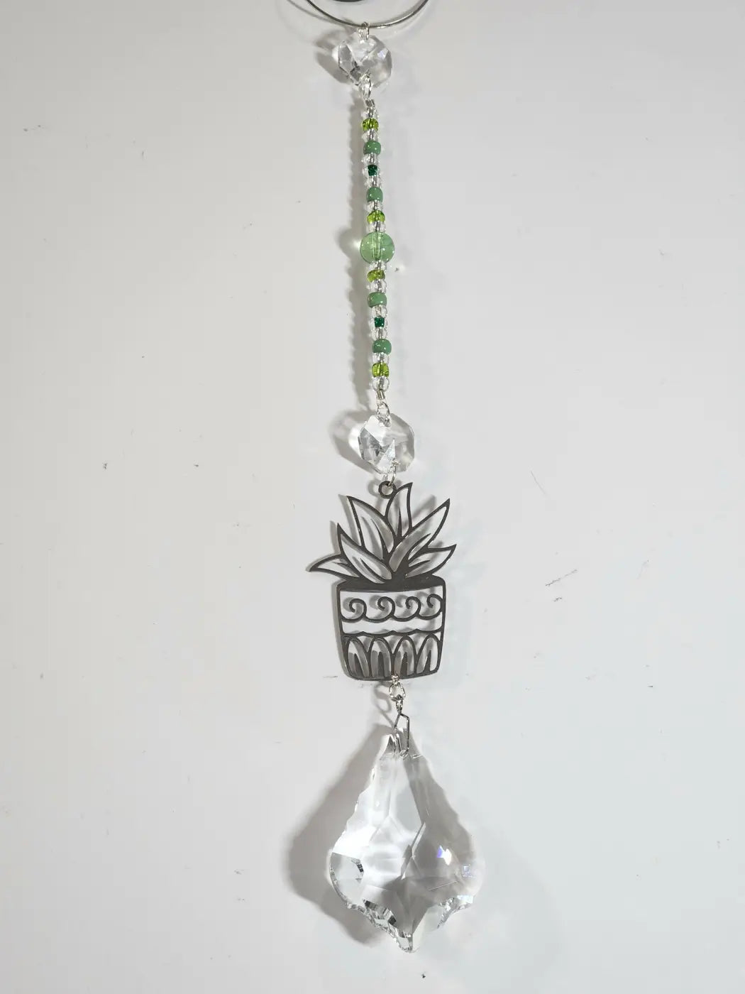 A silver-toned plant long suncatcher with an intricately designed succulent hangs from a chain with an iridescent ornament