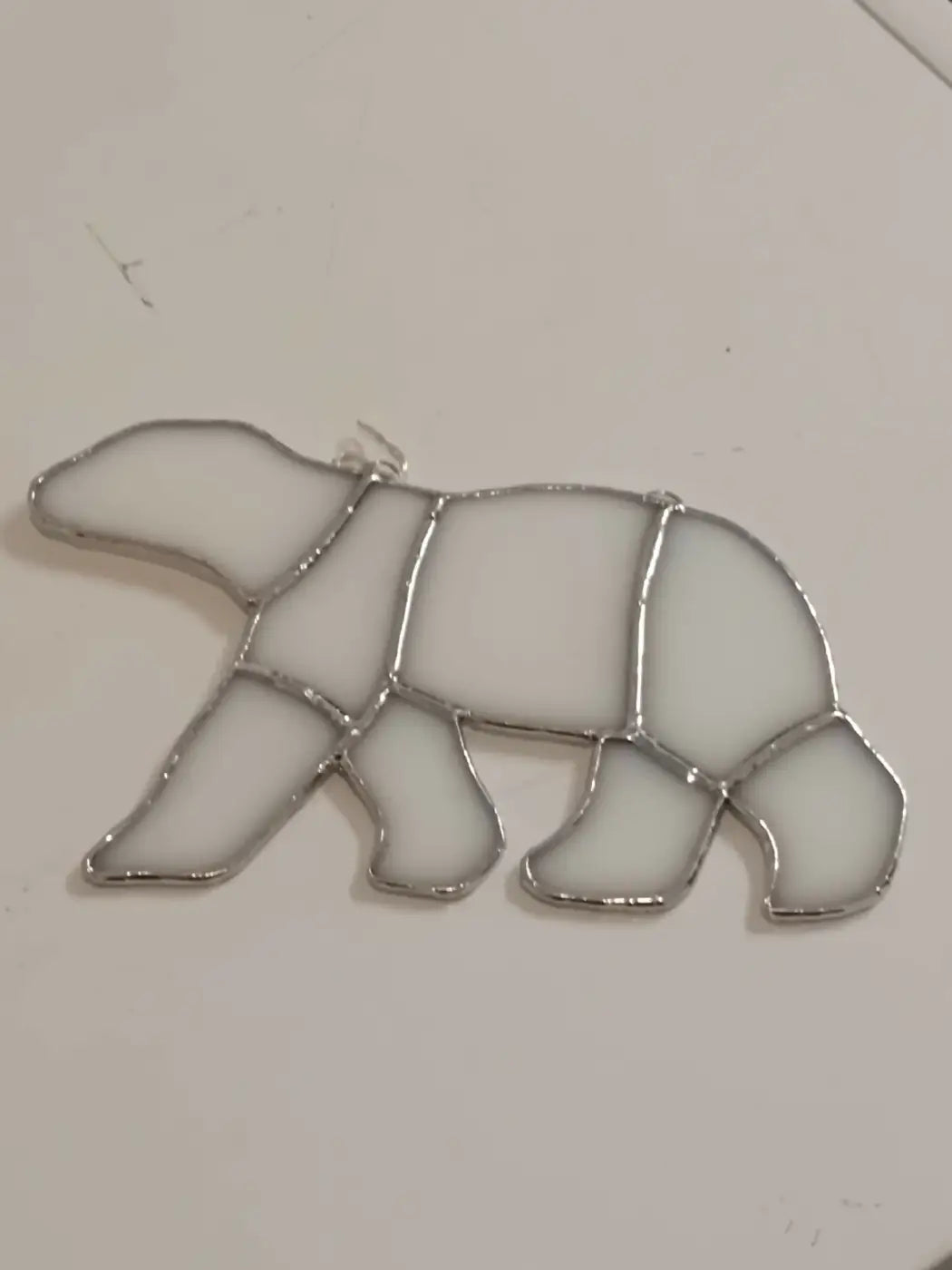 A white stained glass polar bear ornament with a silver metal frame featuring glass polar bear design