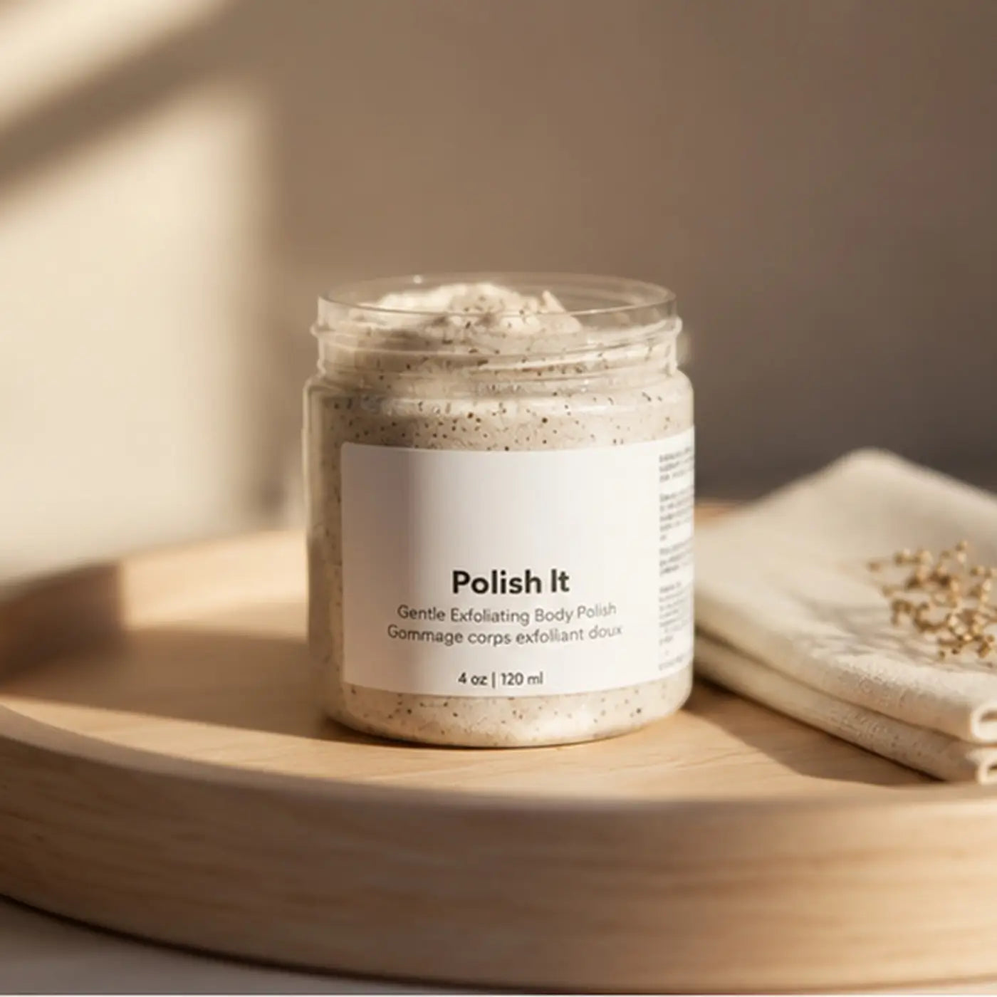 A clear glass jar of beige speckled creamy exfoliant labeled polish it with cucumber seed oil for dead skin removal