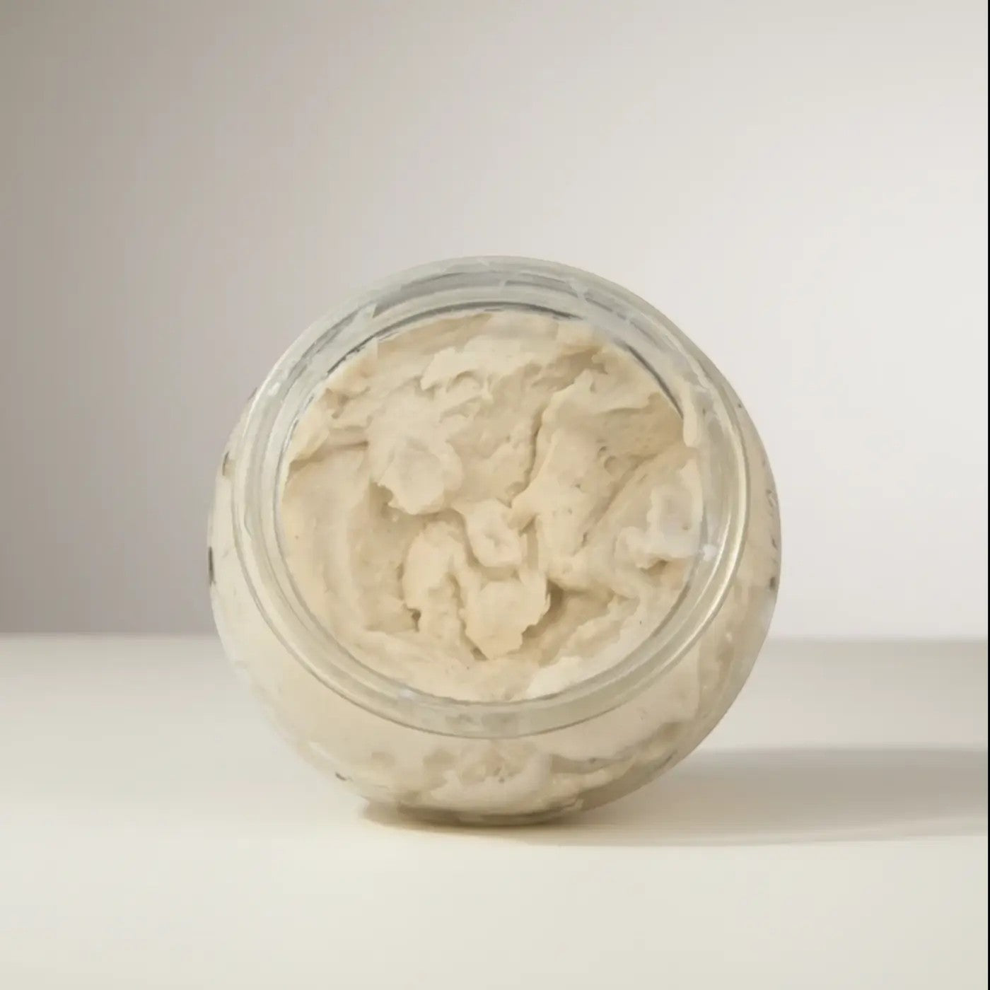 A clear glass jar filled with creamy off-white polish it creamy exfoliant refill for natural skincare canada and pure wash