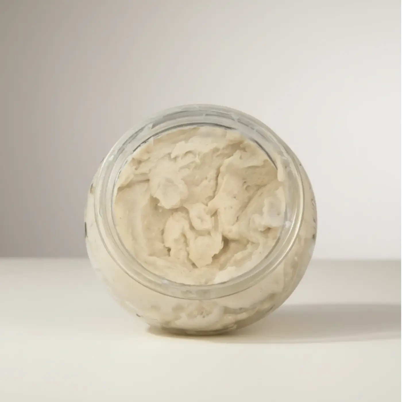 A clear glass jar filled with creamy off-white polish it creamy exfoliant refill for natural skincare canada and pure wash