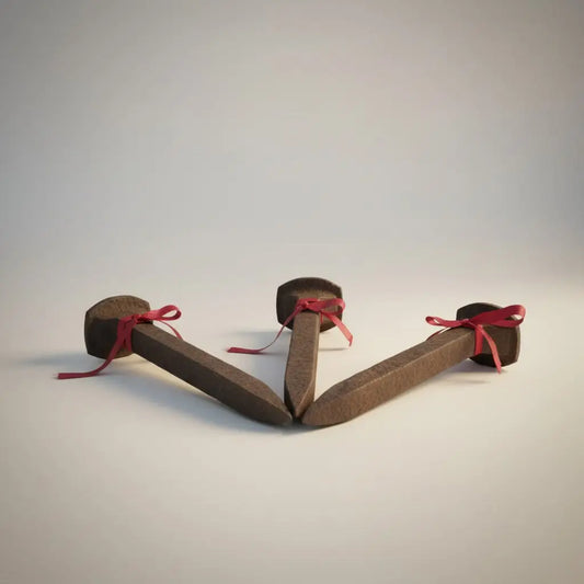 Three dark brown rusted iron spikes tied with red ribbons designed to provide protection from unwanted energy