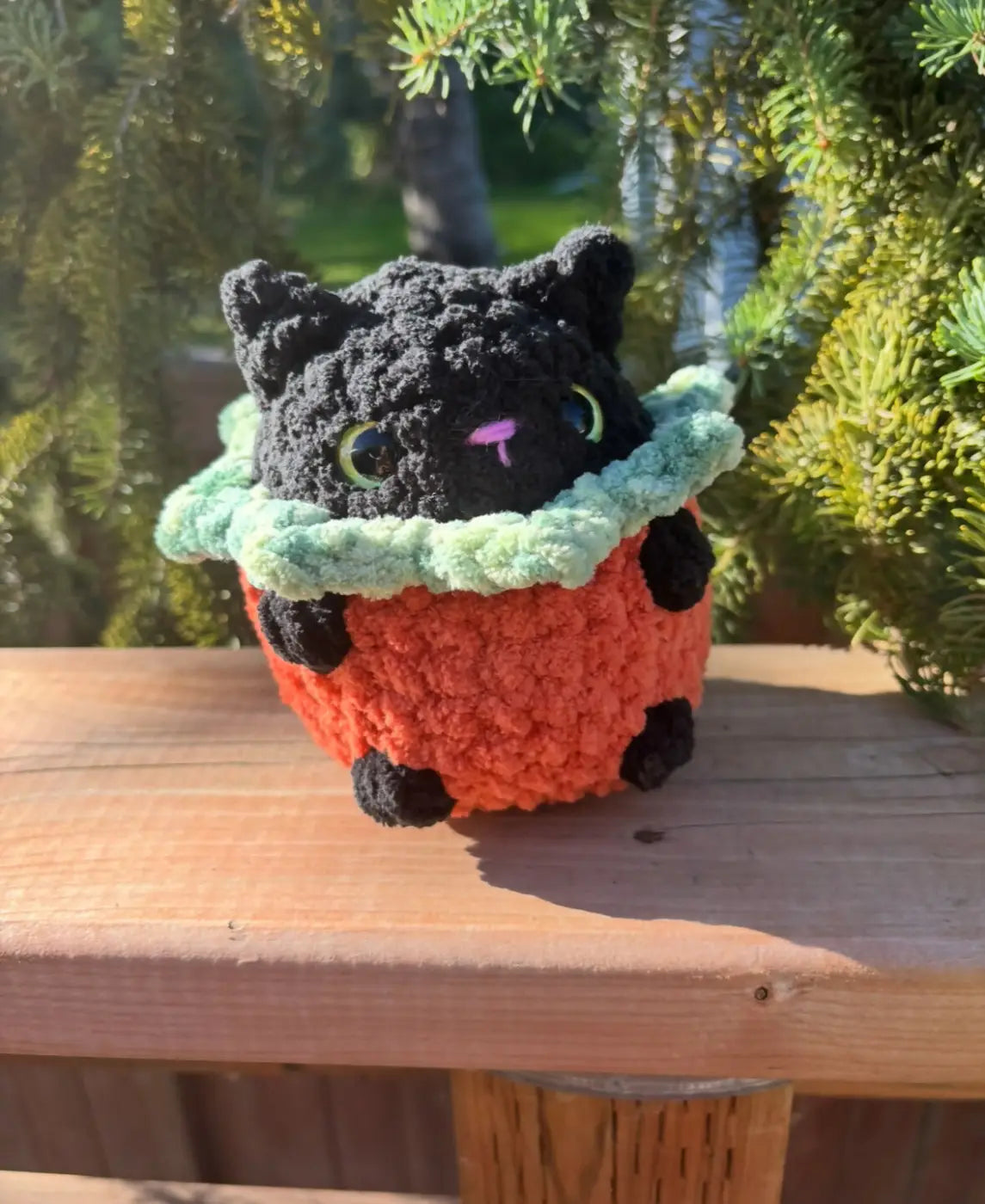 A handmade crocheted black cat with green eyes in an orange pumpkin cat crochet pot natural skincare canada