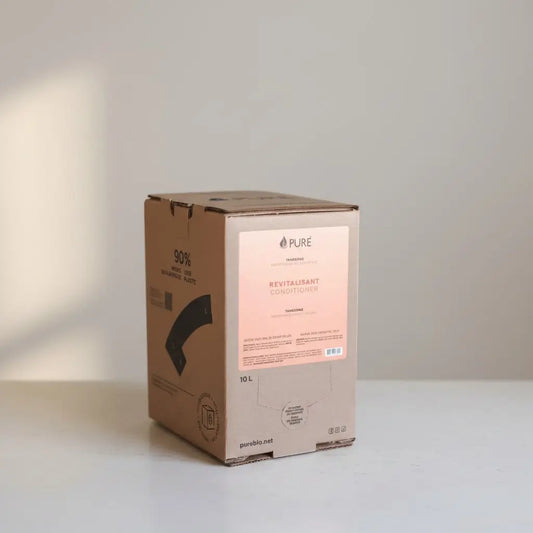 A beige cardboard box with a pink label of pure revitalisant conditioner 10l for in-store refill with moisturizing formula