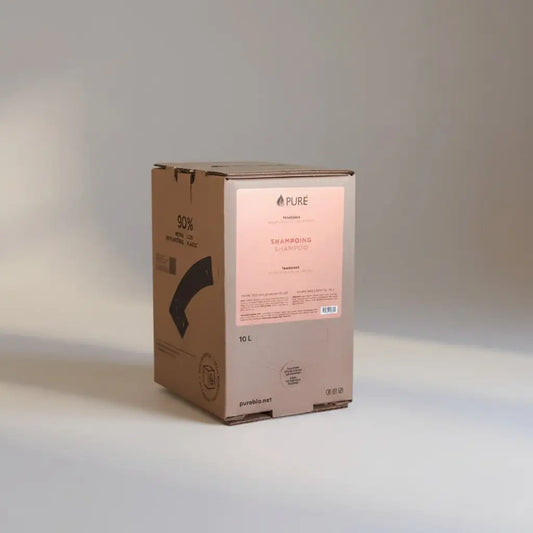 A 10-liter cardboard box of pure shampoo tangerine with a minimalist pink label featuring plant derived cleaning for in-store refill