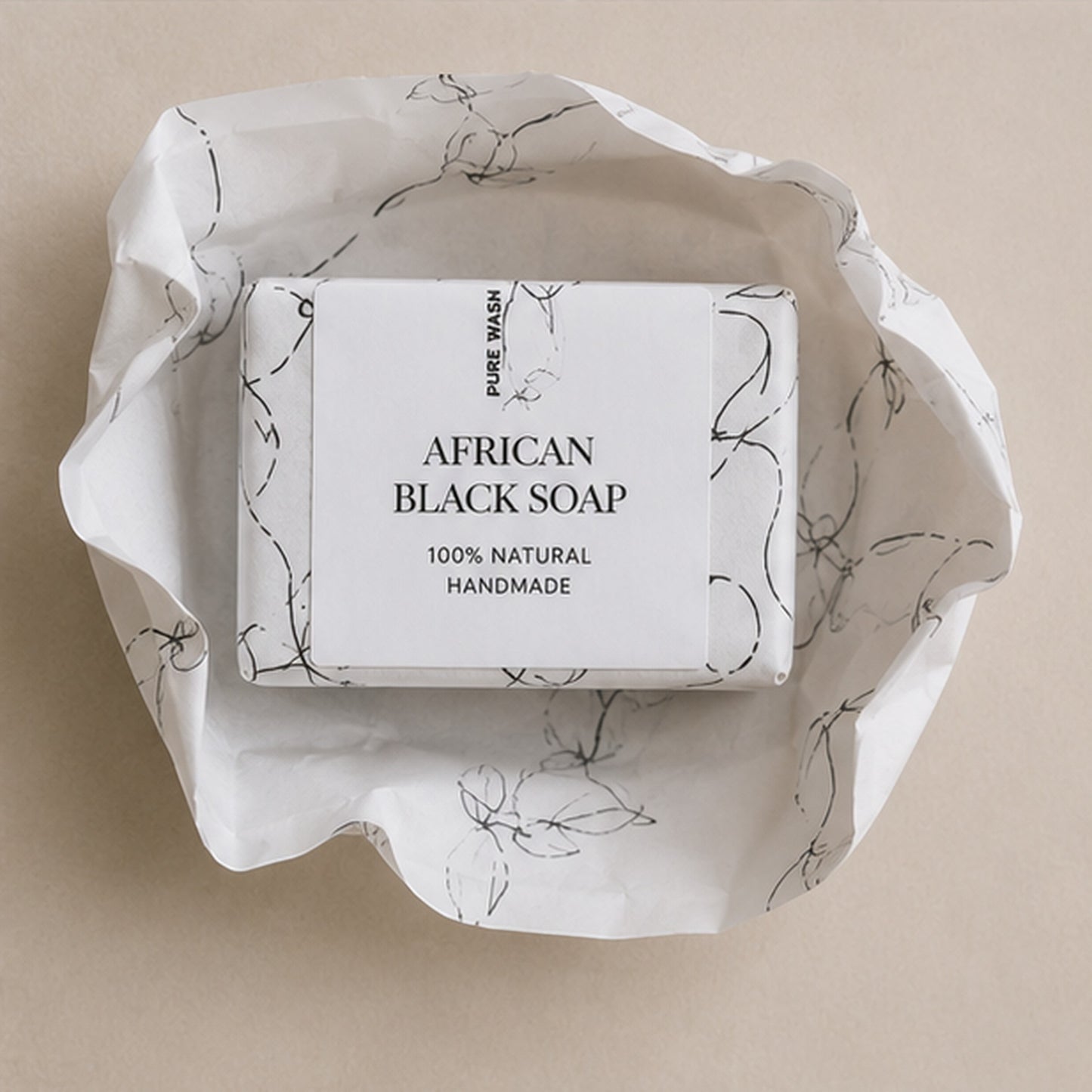 Pure Wash African Black Soap bar wrapped in decorative white paper on a neutral background.