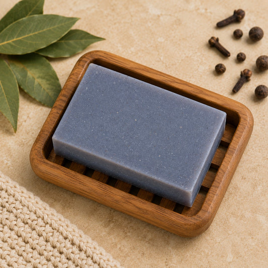 Pure Wash Bay Rum soap bar in a wooden dish with bay leaves, cloves, and a textured cloth on a neutral surface.