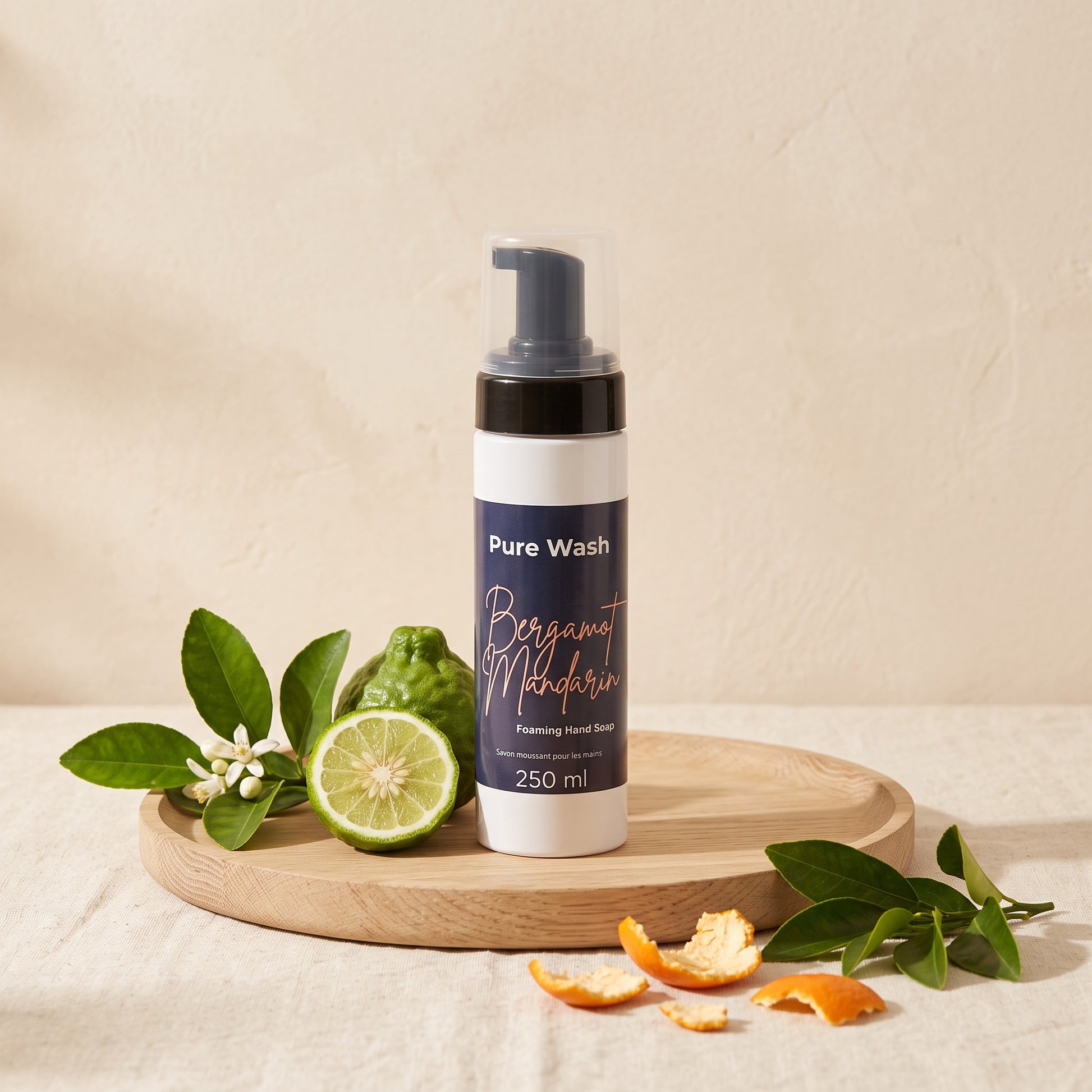 Pure Wash Bergamot Mandarin foaming hand soap in a white bottle on a wooden tray with fresh citrus fruit and leaves.