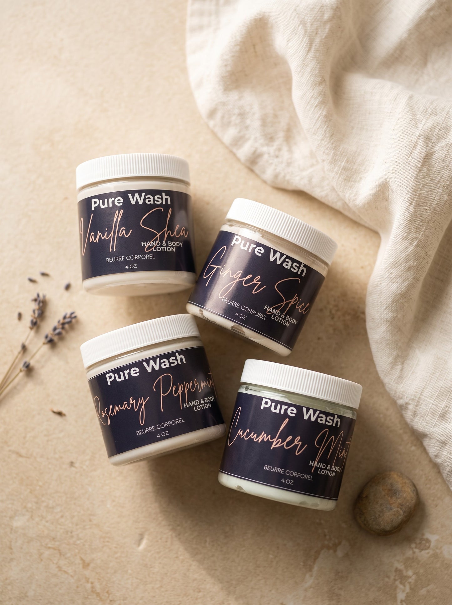 Four Pure Wash body lotion jars in Vanilla Shea, Ginger Spice, Rosemary Peppermint, and Cucumber Mint scents.