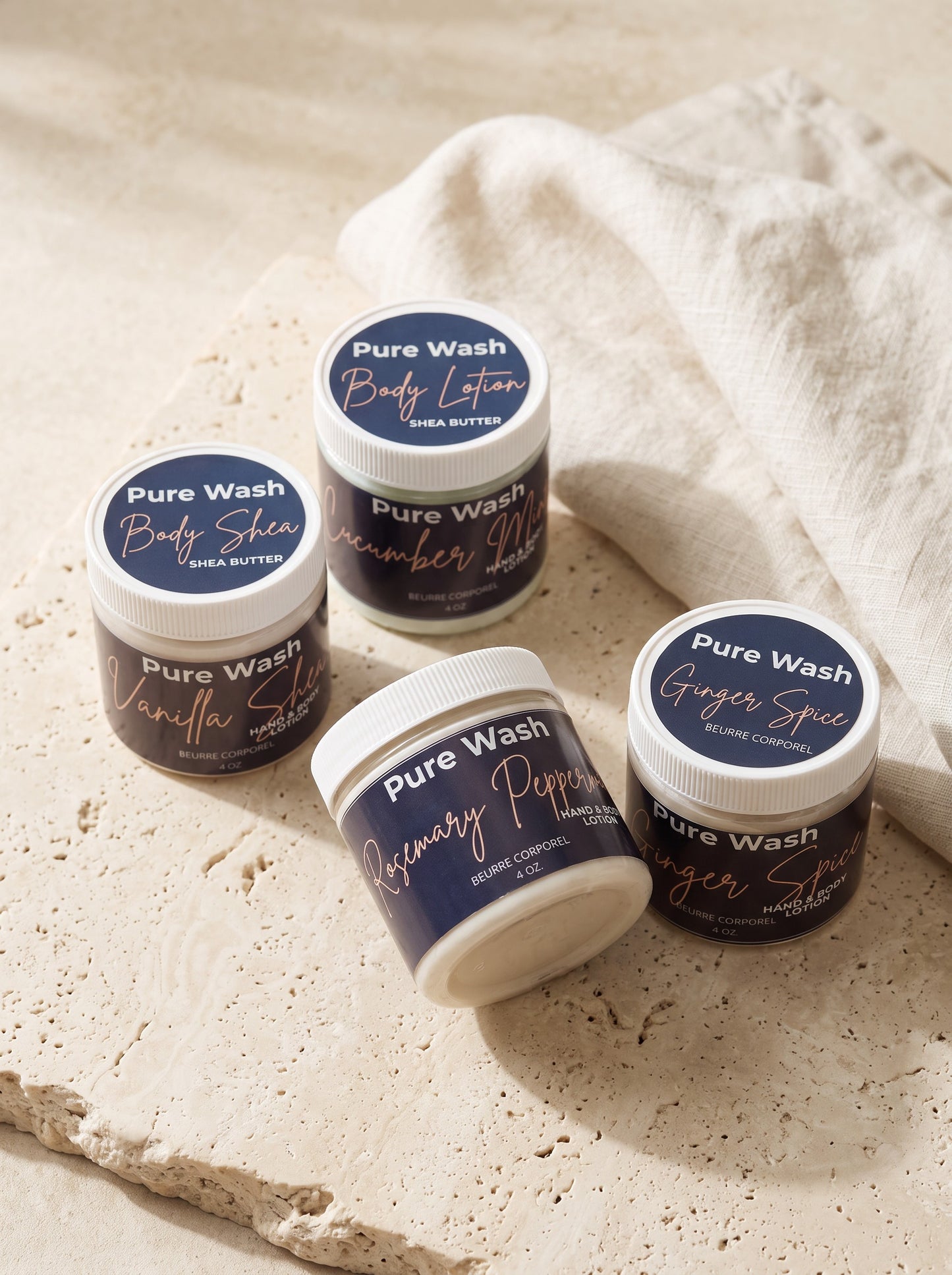 Pure Wash body lotion jars in various scents like vanilla shea and rosemary peppermint on a stone surface