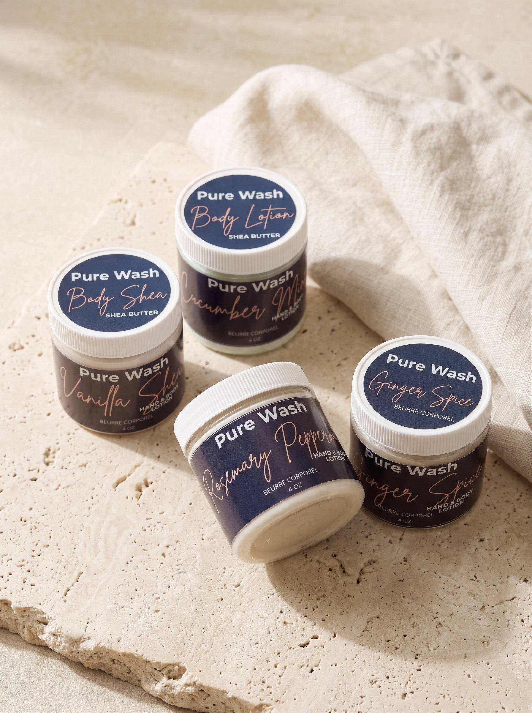 Pure Wash body lotion jars in various scents like vanilla shea and rosemary peppermint on a stone surface