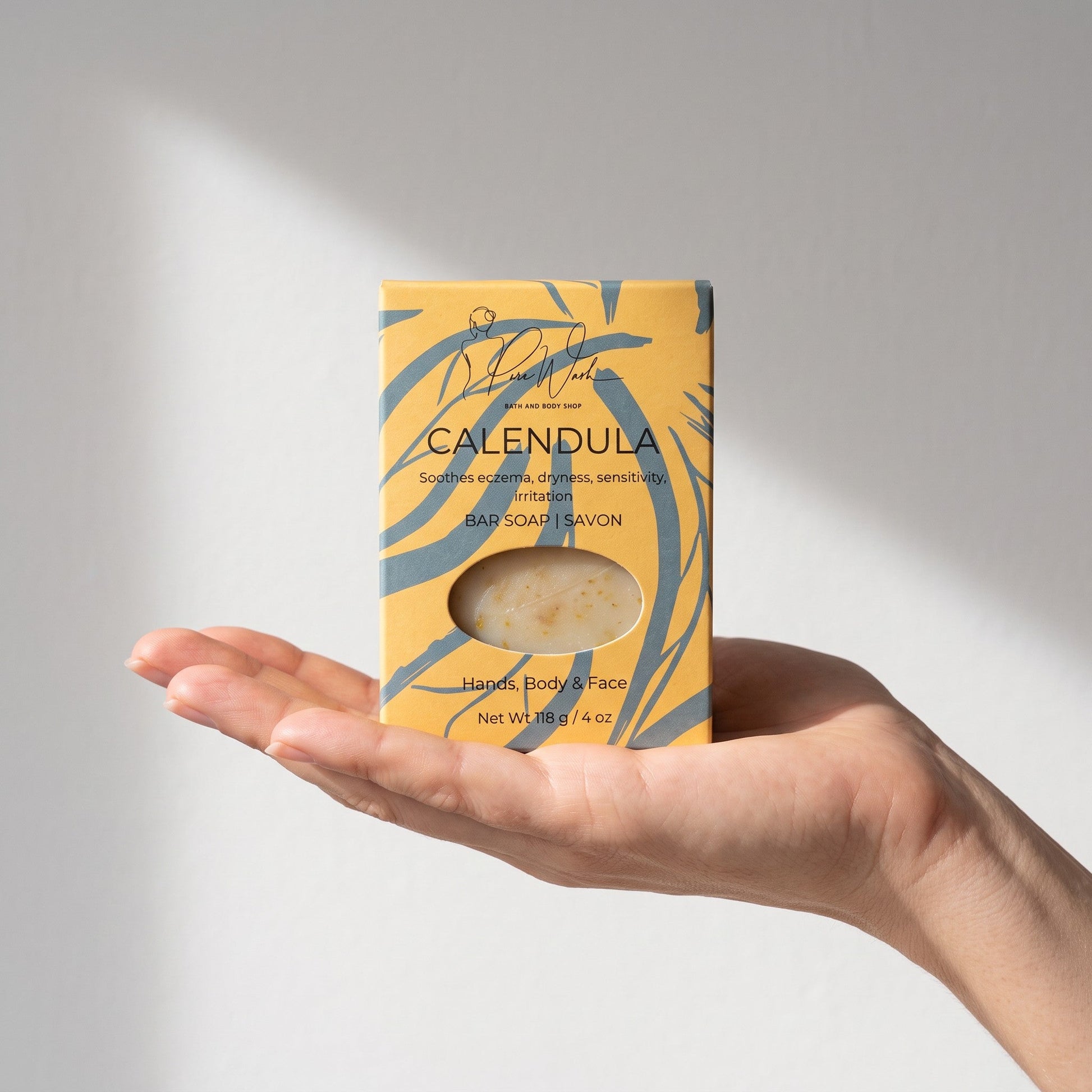 Pure Wash Calendula soap bar in yellow patterned packaging held in a hand, designed for sensitive skin.