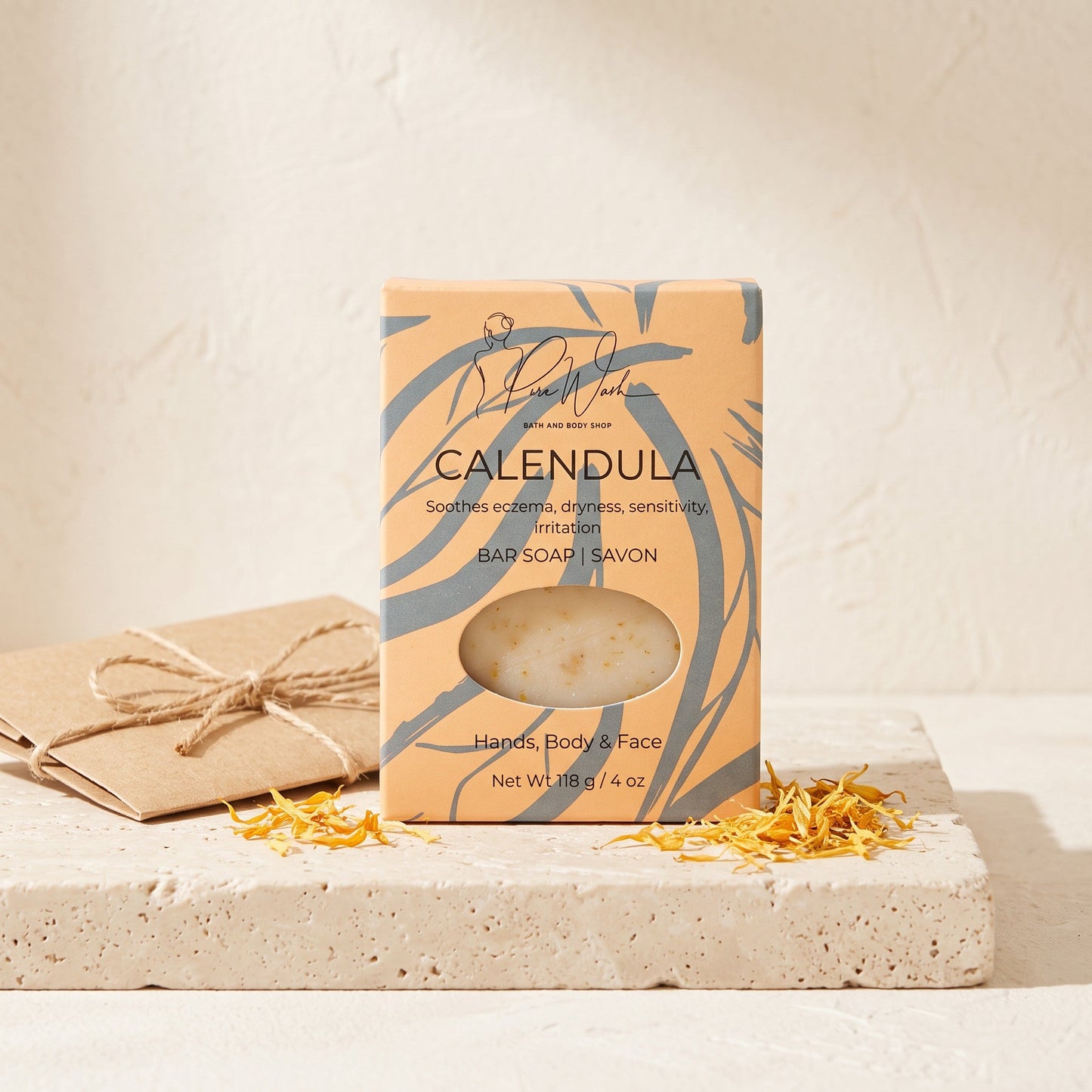 Pure Wash Calendula soap bar in rustic orange packaging with visible petals, sitting on a stone surface.