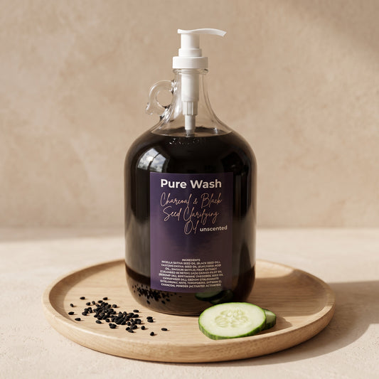 Pure Wash charcoal and black seed clarifying oil in a large glass refill bottle with cucumber and black seeds