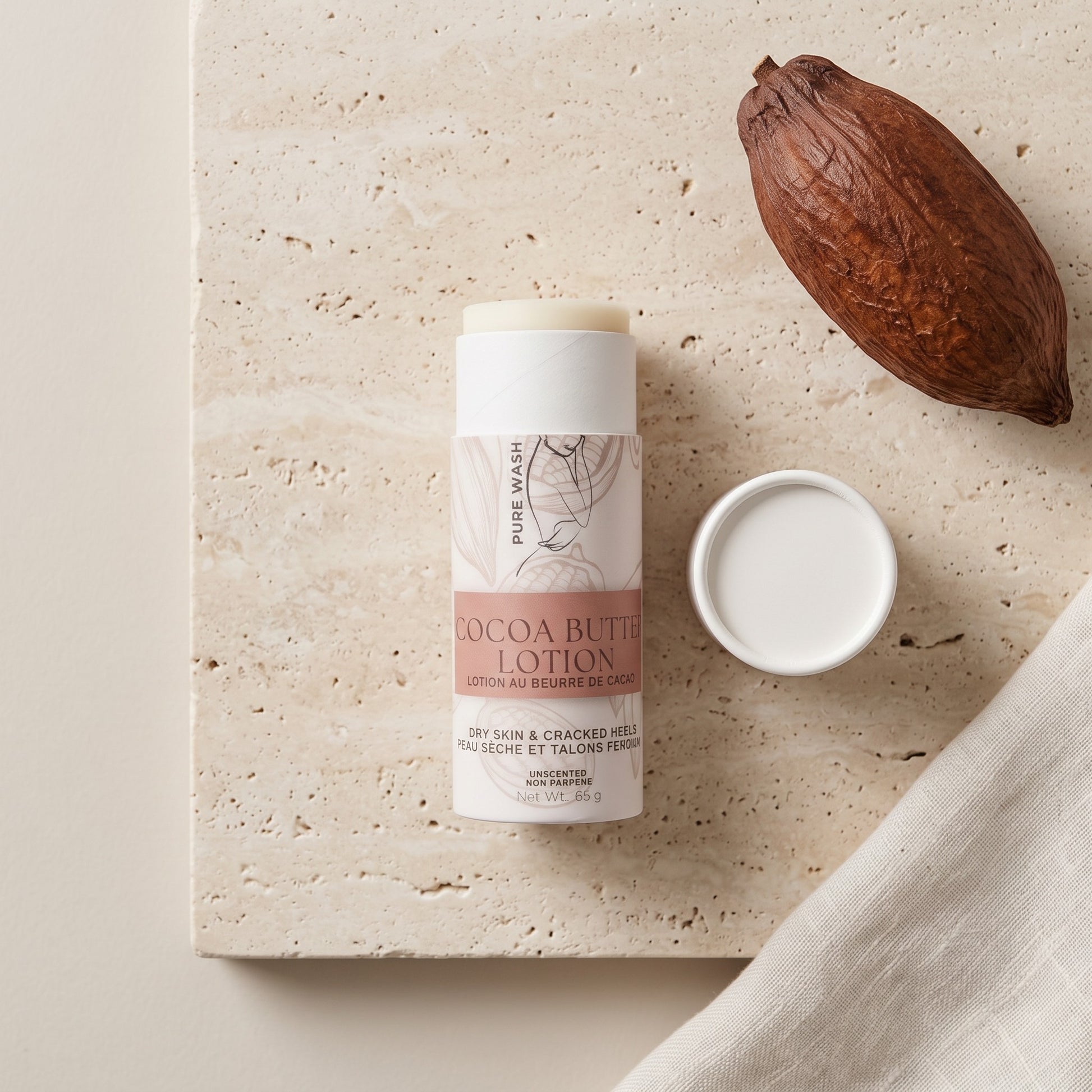 Pure Wash cocoa butter lotion stick for dry skin, featuring shea butter and coconut oil on a textured stone surface.