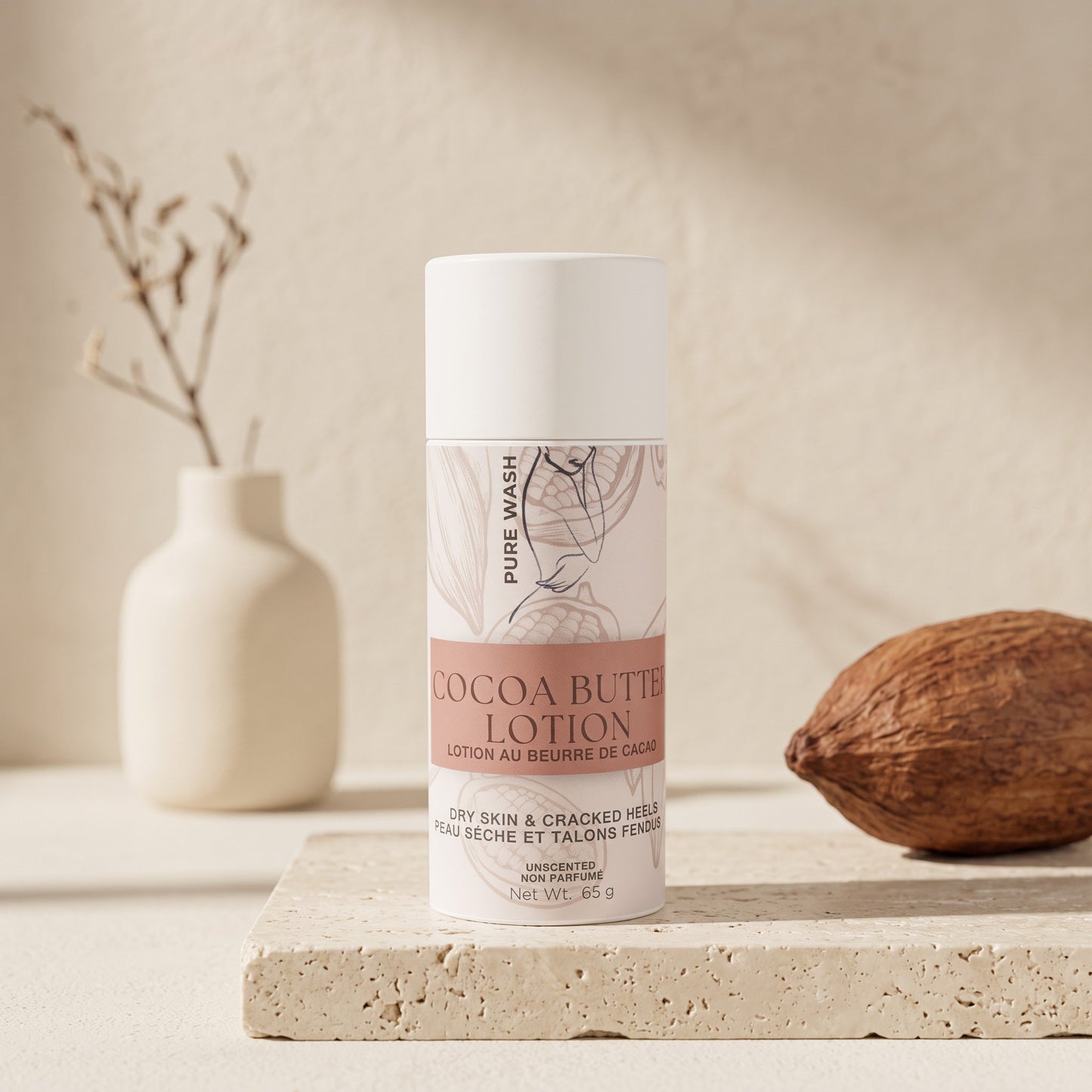 Pure Wash cocoa butter lotion stick in a white tube for dry skin, displayed on a stone surface with a cacao pod.