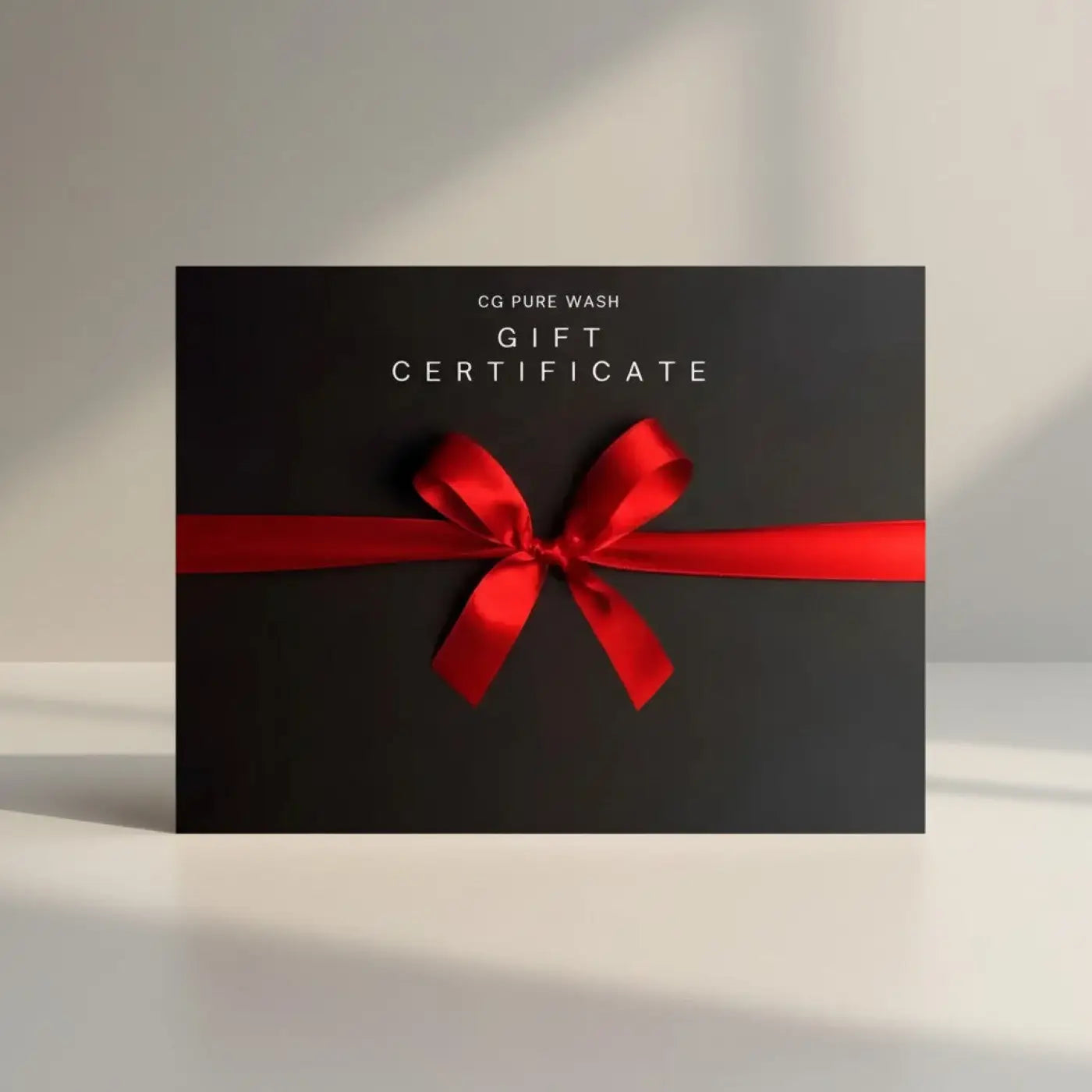Pure Wash gift certificate with a red satin ribbon and bow on a black background.