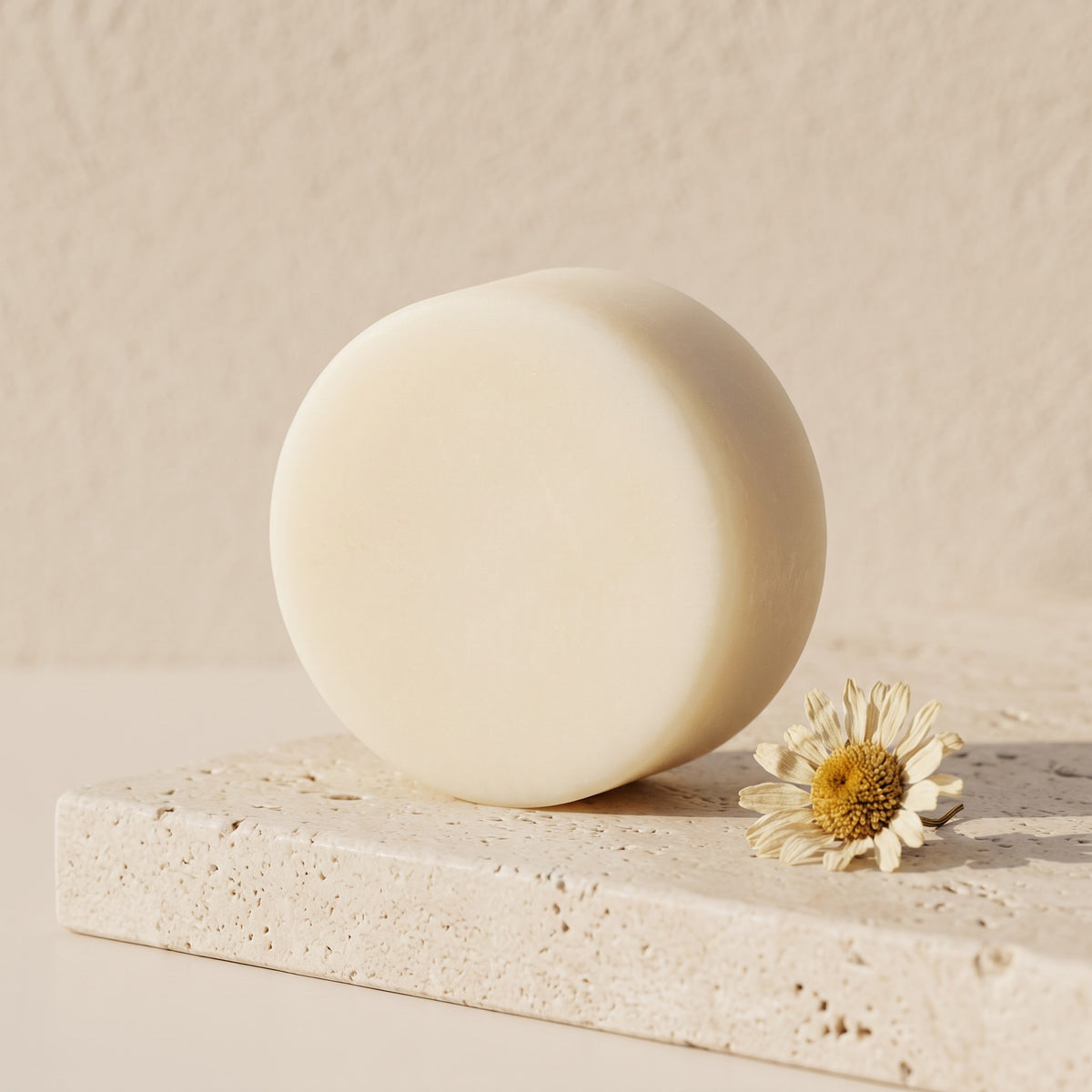 Pure Wash lavender chamomile solid conditioner bar with shea butter and oils on a textured stone surface with a flower