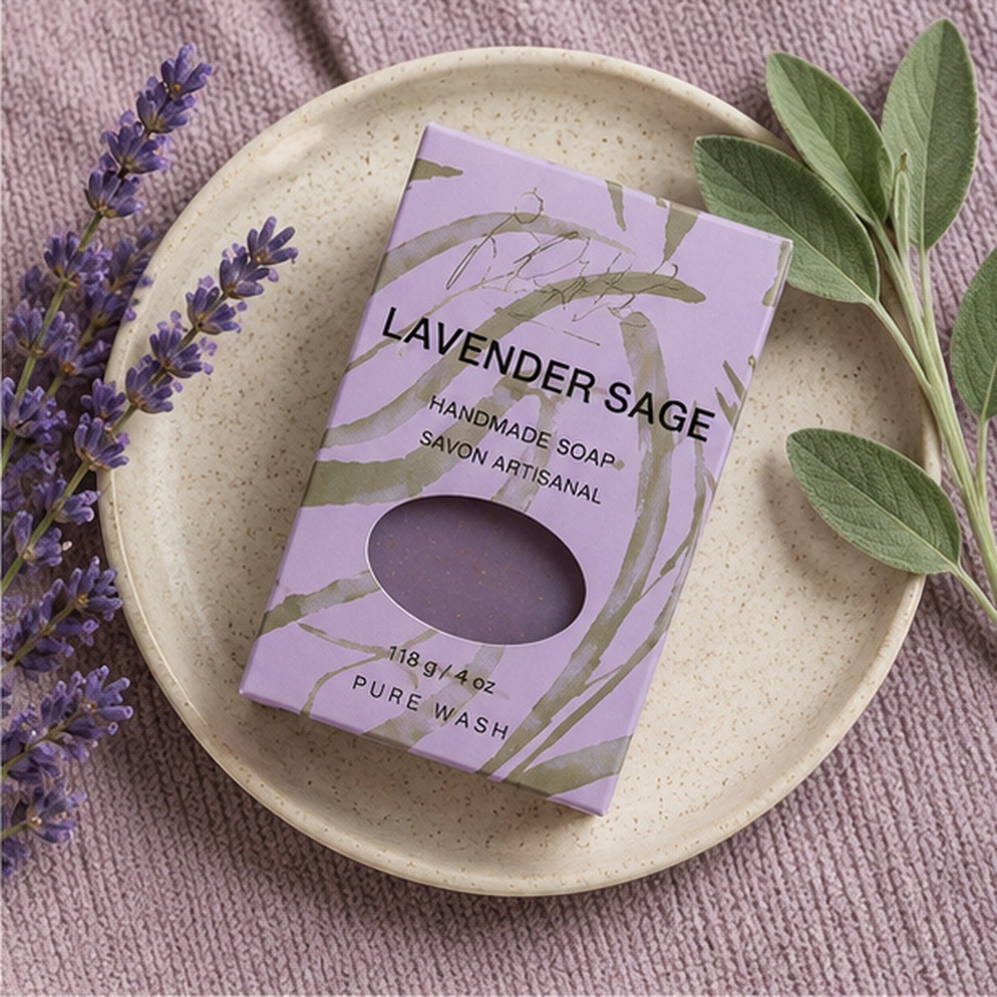Pure Wash Lavender Sage handmade soap bar in purple packaging on a ceramic plate with fresh lavender and sage sprigs.