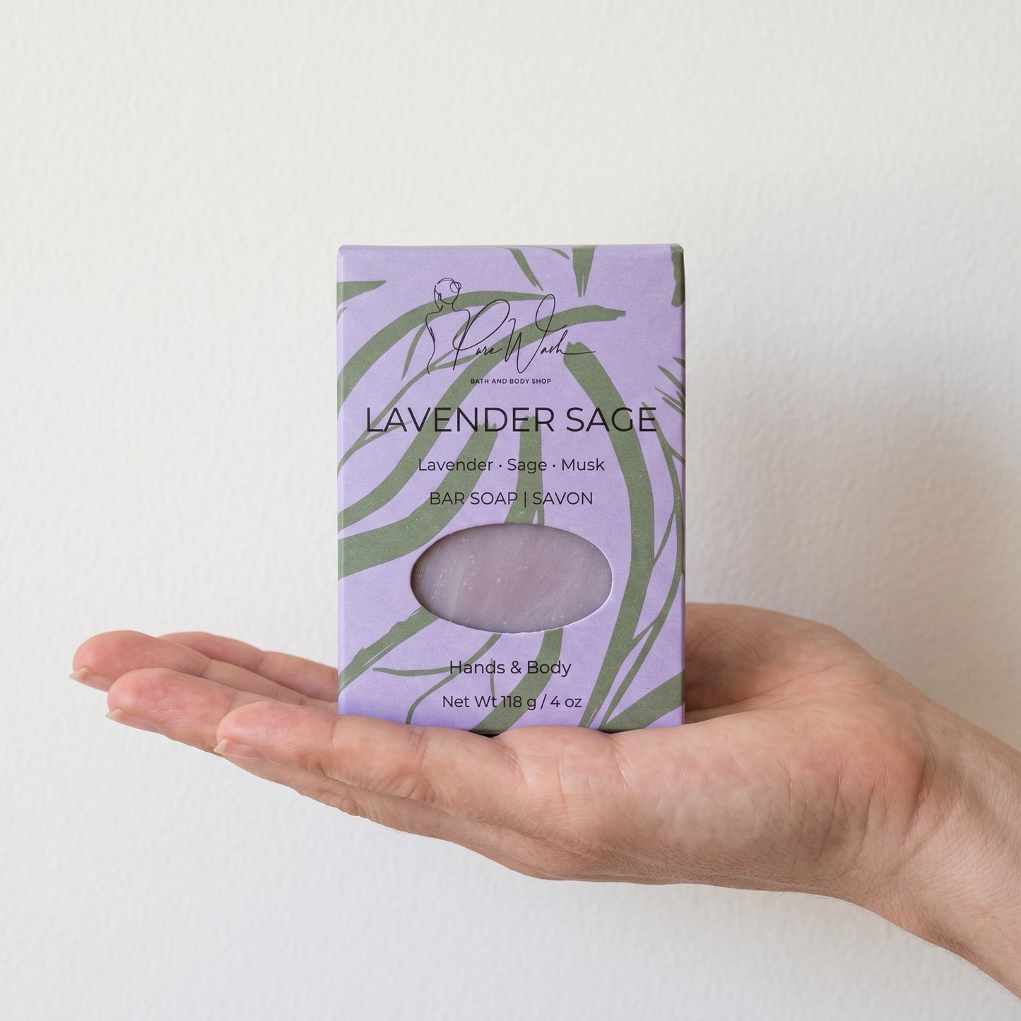 Pure Wash Lavender Sage soap bar in a light purple botanical patterned box held in a palm