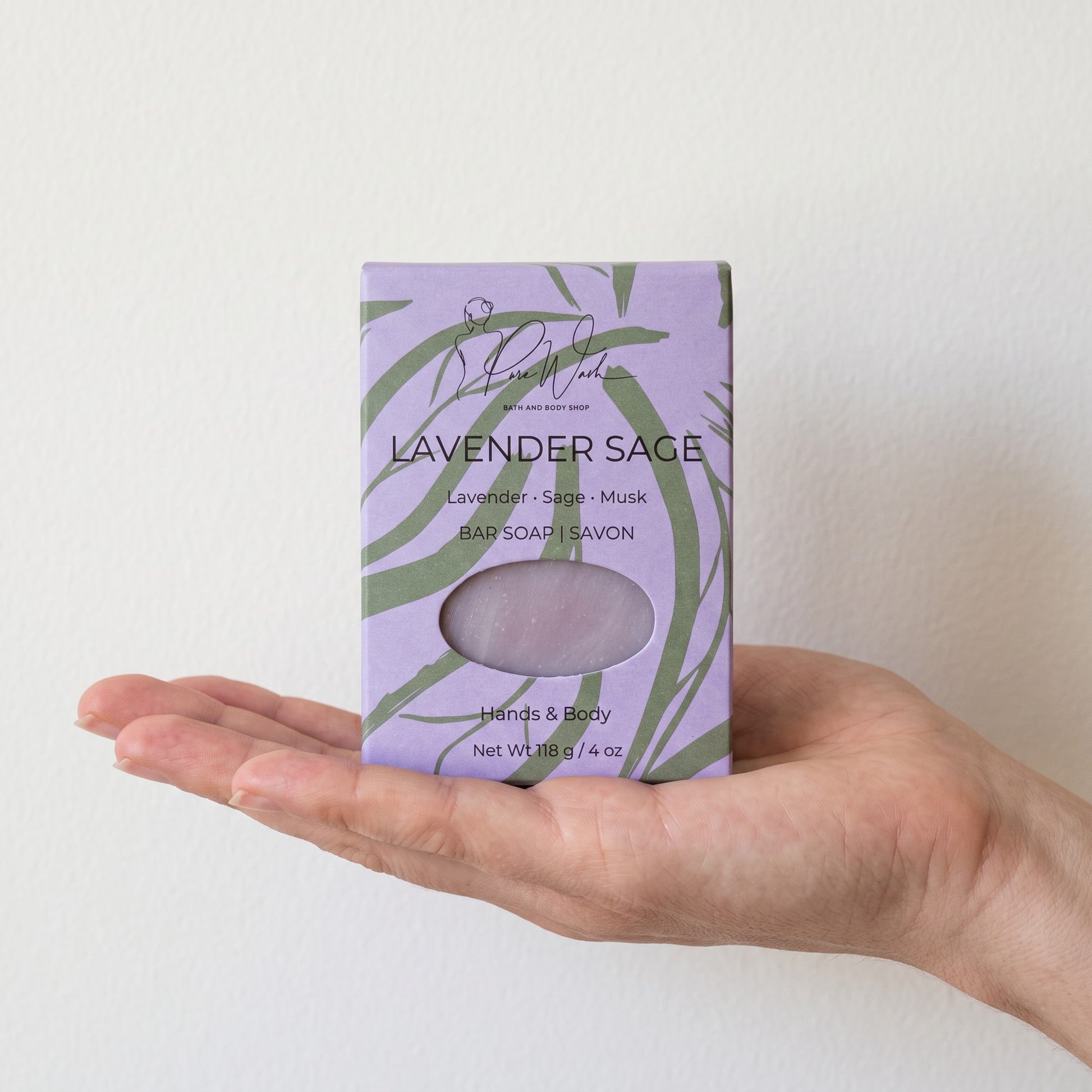 Pure Wash Lavender Sage soap bar in a light purple botanical patterned box held in a palm