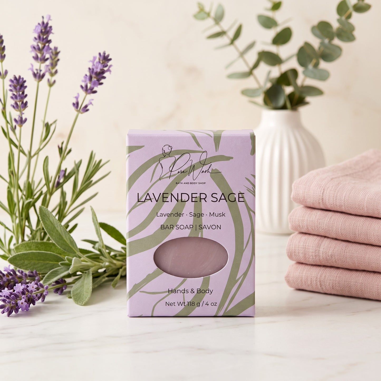 Pure Wash Lavender Sage soap bar in light purple packaging with lavender sprigs and folded pink towels on marble