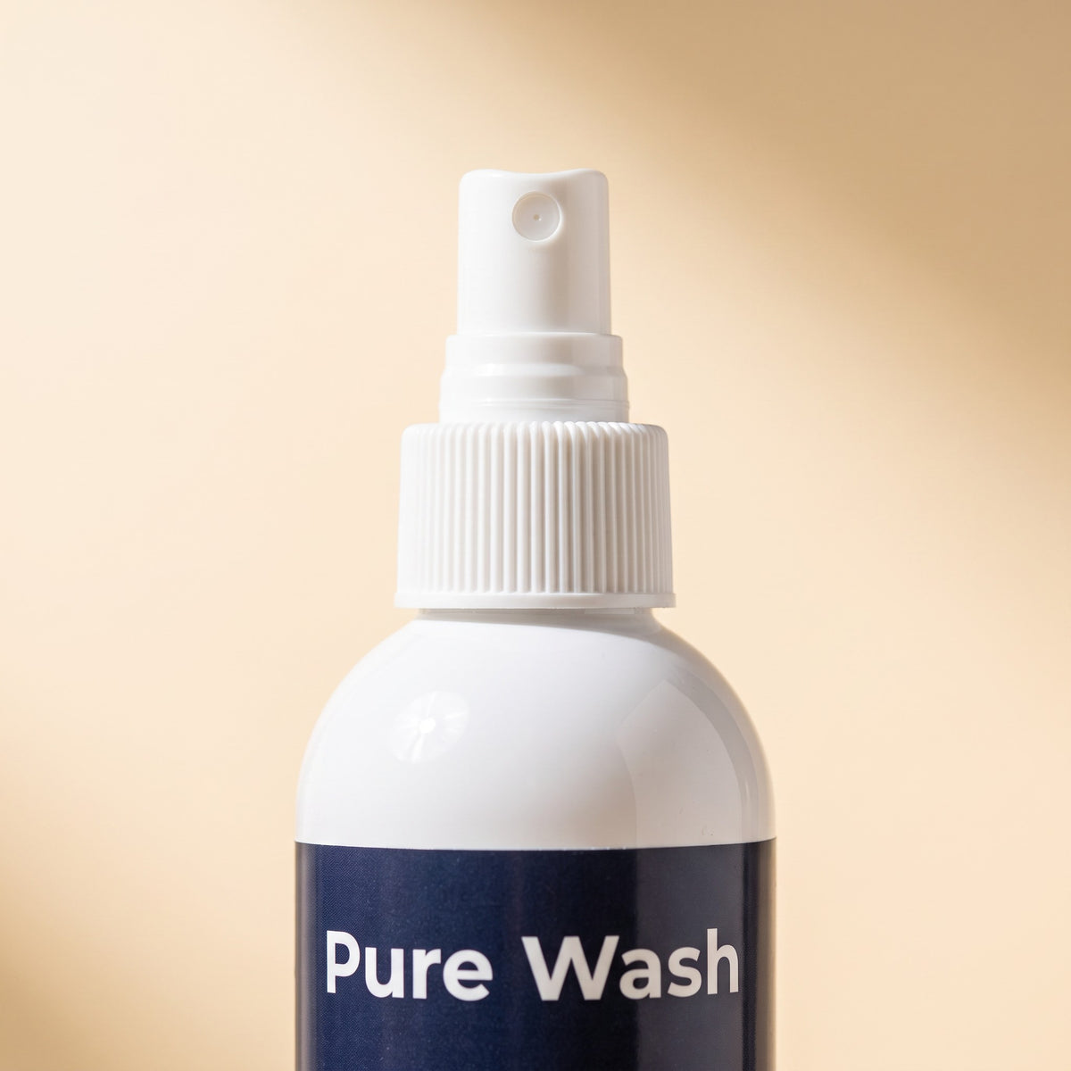 Pure Wash leave-in mermaid hair conditioner spray in a white bottle with a spray nozzle against a beige background.