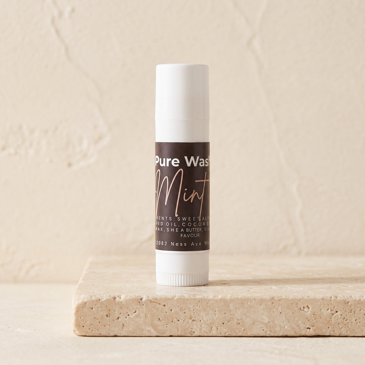 Pure Wash mint lip balm in a slim white tube, formulated with beeswax, shea butter, and coconut oil.