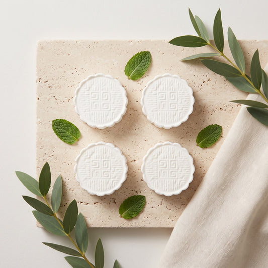 Pure Wash mint-scented shower steamers on a stone tile with fresh mint leaves and eucalyptus sprigs.