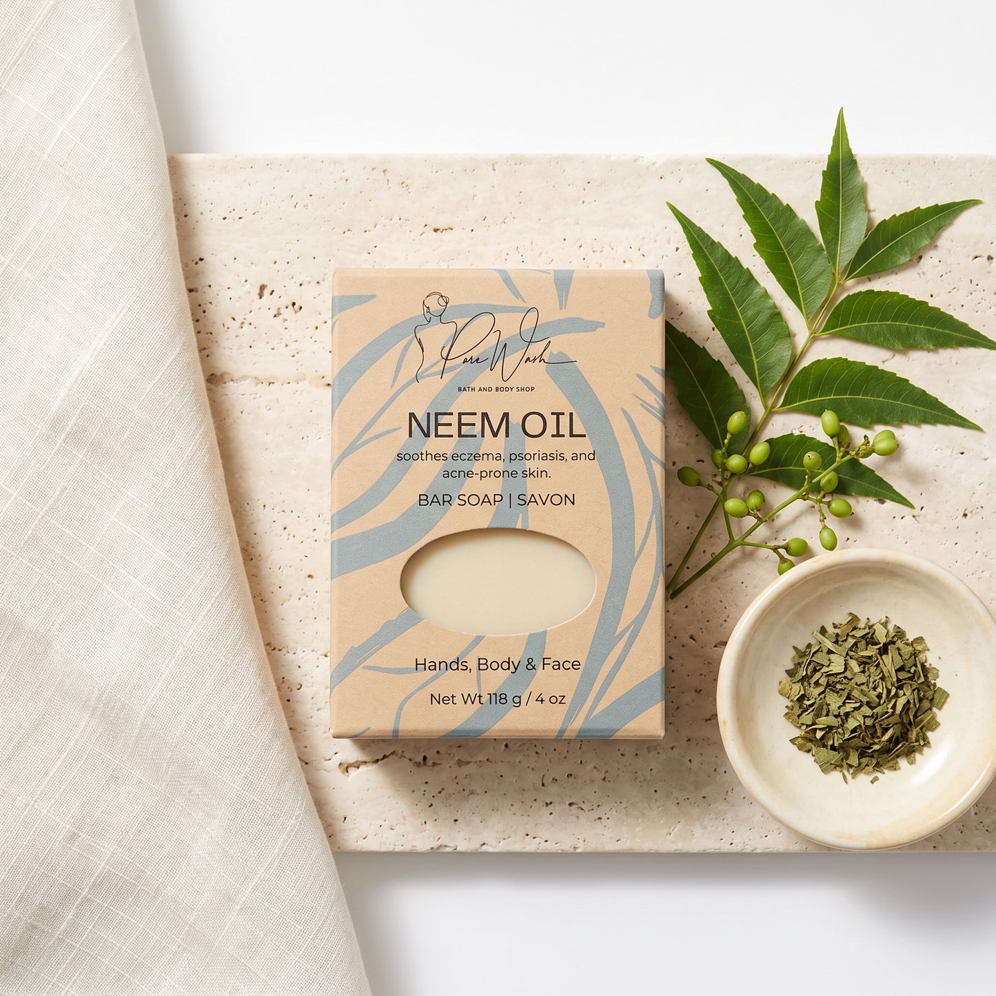 Pure Wash neem oil soap bar in kraft paper packaging on a stone surface with fresh neem leaves and dried herbs.