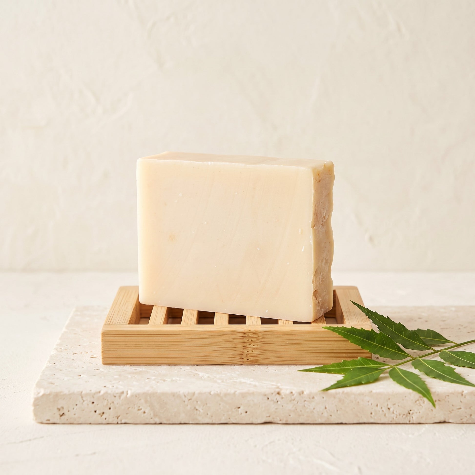Pure Wash unscented neem oil soap bar on a bamboo dish with a green leaf on a textured stone surface