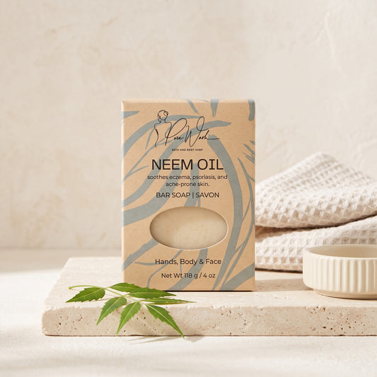 Pure Wash Neem Oil soap bar in eco-friendly packaging on a stone tray with a green leaf and white towel