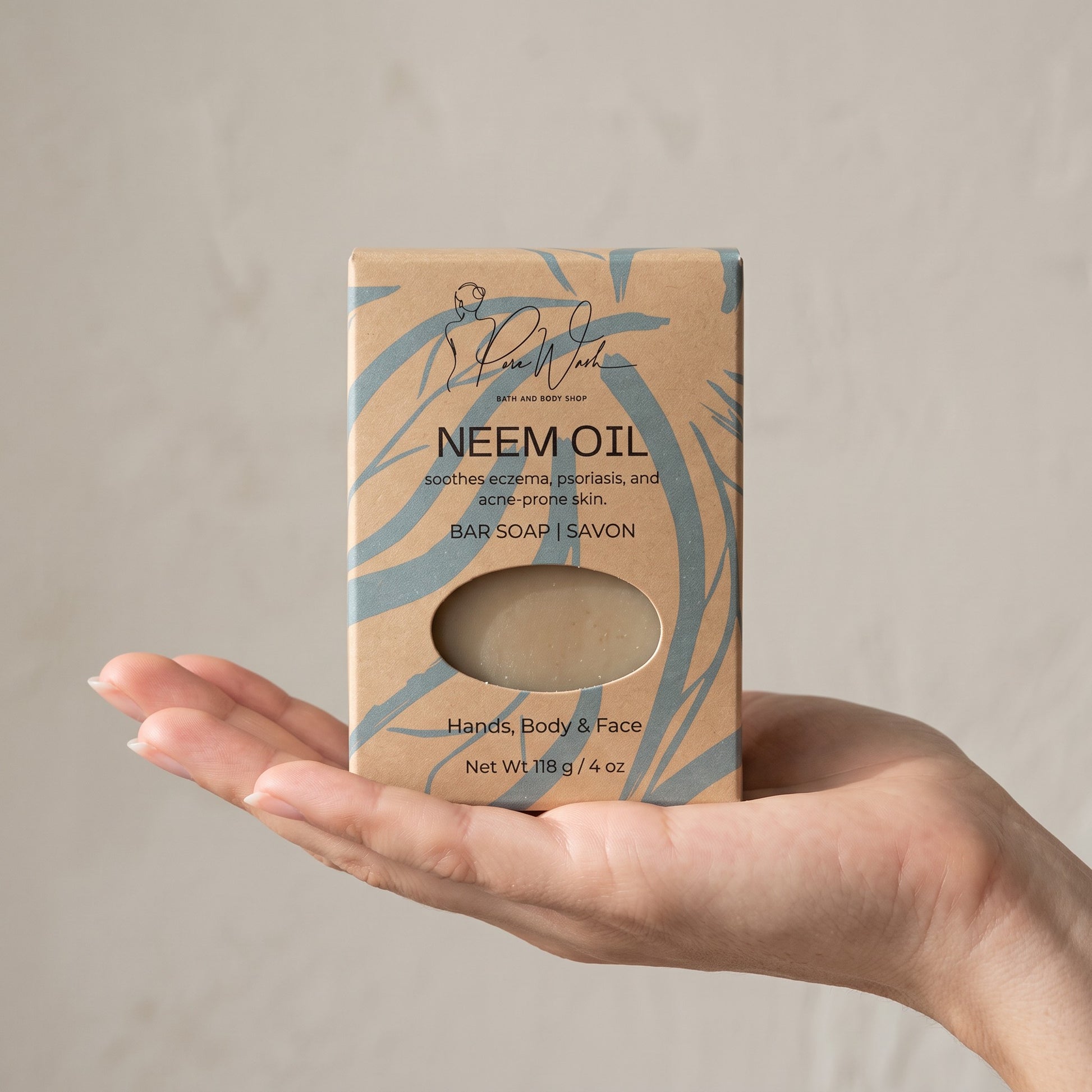 Pure Wash neem oil soap bar in eco-friendly kraft paper packaging held in a hand for face and body use